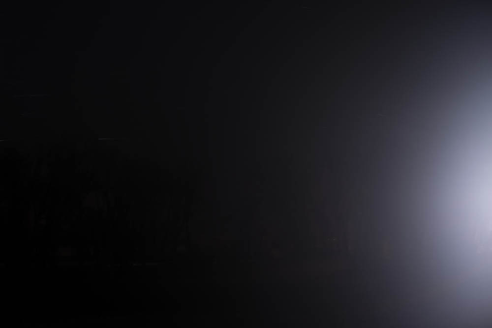 Blast of light/night: car headlight in foggy Wyoming night
